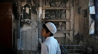 Seorang anak melihat masjid yang dibakar massa dalam bentrokan di New Delhi pada Kamis (27/2) kemarin. AP Photo/Altaf Qadri.