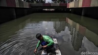 Salah seorangnya terlihat tengah mencuci sepatu di genangan air tersebut.