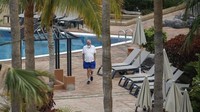 Seorang turis tengah berjalan-jalan di sekitar kolam renang yang berada di sebuah hotel yang berada di kawasan Tenerife, Kepulauan Canary, Spanyol. Ribuan tamu di hotel itu dikarantina terkait virus corona usai satu orang turis Italia dinyatakan positif COVID-19.