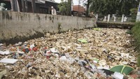 Warga melintas di samping kali Licin yang dipenuhi sampah di Depok, Jawa Barat, Jumat (28/2/2020).