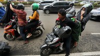 Sejumlah pengemudi ojek online (ojol) yang masih mengangkut penumpang berganti jaket guna menghindari sweeping aksi demo yang digelar di kawasan Gedung Parlemen, Senayan, Jakarta, Jumat (28/2/2020).