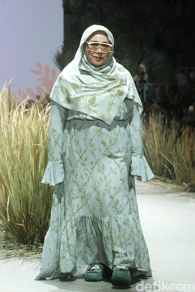 Ini penampilan Melly Goeslow mengenakan hijab Murni series dari L by LCB milik Laudya Cynthia Bella. Pelantun lagu Gantung ini pun berjalan di panggung runway dengan busana bernuansa toska dan sneakers. Foto: Mohammad Abduh/Wolipop