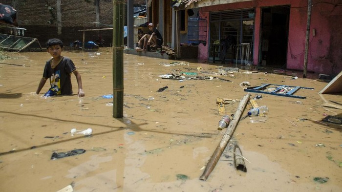 Seorang anak melintasi genangan banjir di Kawasan Sayang, Jatinangor, Sumedang, Jawa Barat, Sabtu (29/2/2020). Sedikitnya 2.000 jiwa dari 660 kepala keluarga di lima area kawasan Jatinangor tersebut terdampak banjir bandang yang menyebabkan sejumlah pemukiman rusak berat dan ringan karena meluapnya aliran sungai Cikeruh pada Jumat (28/2/2020) lalu. ANTARA FOTO/Novrian Arbi/aww.