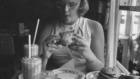 Memakai kacamata vintage, wanita ini dengan lahap menikmati hamburger kesukannya di New York Citys Greenwich Village. Foto: Istimewa