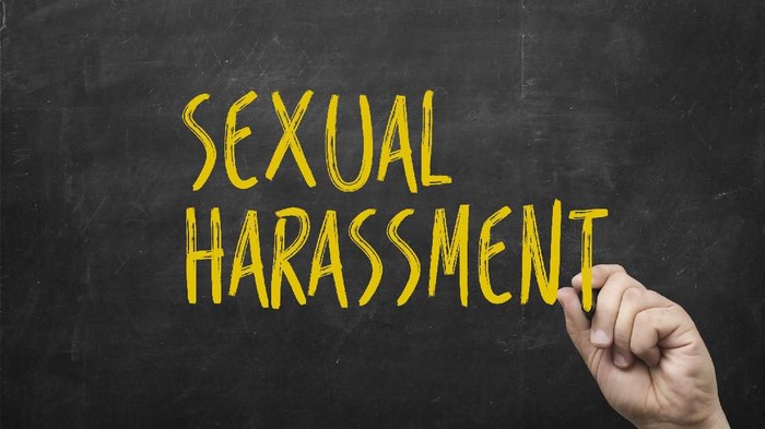 hand writing sexual harassment on blackboard. Symbol of violence against women