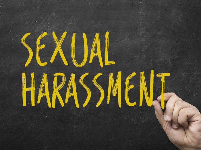 hand writing sexual harassment on blackboard. Symbol of violence against women