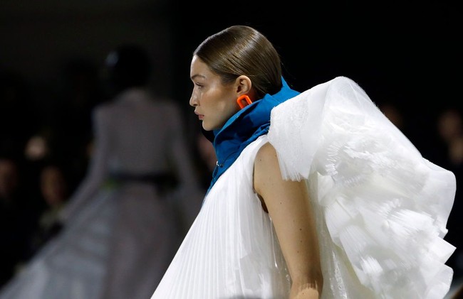 Gayanya kian dramatis dengan tumpukan ruffle di bagian belakang gaun. Gayanya kian sempurna dengan statement necklace dan heels biru bergaya futuristik.  Foto: Getty Images/Thierry Chesnot