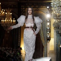 Model 23 tahun itu menggunakan gaun putih berbahan laser cut. Bagian lengannya dibuat bervolume.  Foto: Getty Images/Thierry Chesnot