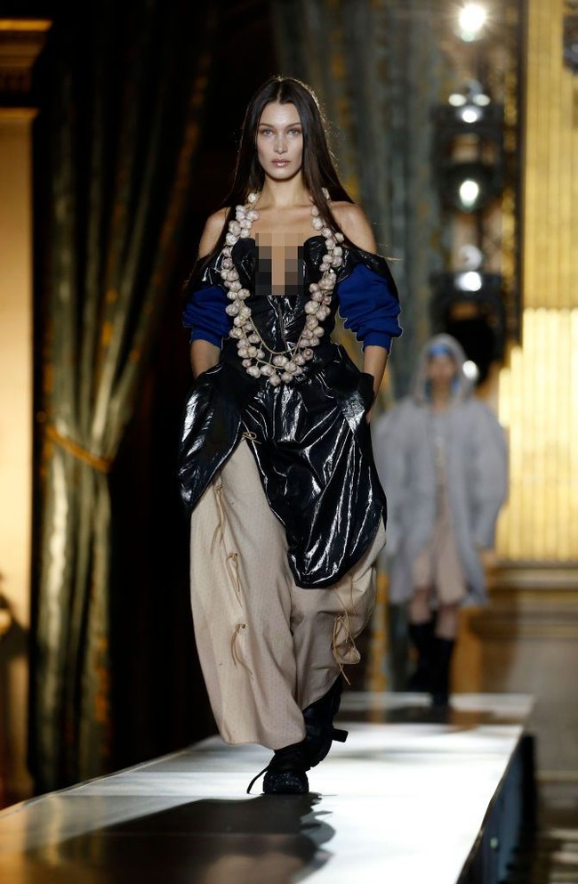 Sebelum menggunakan busana putih bak pengantin, Bella tampil tak kalah seksi mengenakan busana berbahan plastik PVC. Penampilannya pun tersebut unik dengan menggunakan kalung dari tumpukan bawang putih.  Foto: Getty Images/Thierry Chesnot