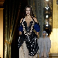 Sebelum menggunakan busana putih bak pengantin, Bella tampil tak kalah seksi mengenakan busana berbahan plastik PVC. Penampilannya pun tersebut unik dengan menggunakan kalung dari tumpukan bawang putih.  Foto: Getty Images/Thierry Chesnot