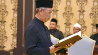 Muhyiddin dengan mengenakan busana melayu hitam-hitam dengan peci warna hitam menyampaikan sumpah di depan raja. Maszuandi Adnan/Malaysias Department of Information via AP.