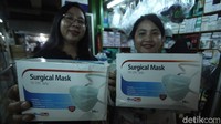 Dua orang pembeli memamerkan masker yang baru di beli di depan kamera.
