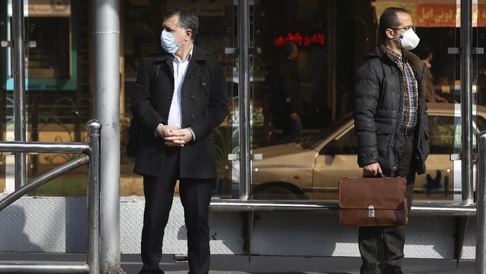 Men wearing face masks wait for a bus in northern Tehran, Iran, Sunday, March 1, 2020. While the new coronavirus has extended its reach across the world, geographic clusters of infections were emerging, with Iran, Italy and South Korea seeing rising cases. (AP Photo/Vahid Salemi)