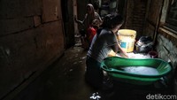 Seorang warga tampak sedang mencuci pakaian di tengah banjir yang merendam tempat tinggalnya.