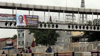 Seorang warga melintasi JPO yang di salah satu sisinya terpasang spanduk bertuliskan Terima Kasih Pak Anies, Banjir Udeh Surut Seneng Warganye Maju Terus Yee..!!.