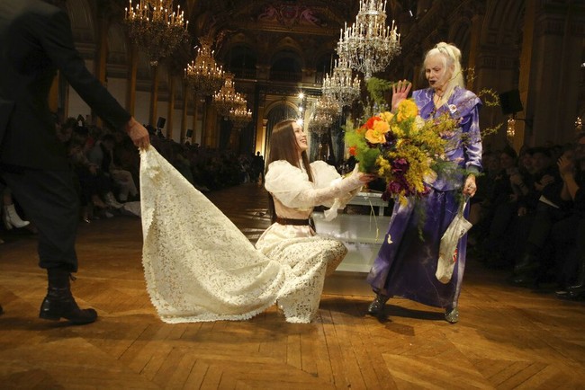 Look kedua yang diperagakan Bella Hadid adalah gaun pengantin menerawang dengan lengan bervolume dramatis. Sabuk yang dilengkapi tempat pisau menjadi aksesori andalan. Tampilan busana tersebut sekaligus menjadi penutup manis fashion show Vivienne Westwood.  (Foto: Vianney Le Caer/Invision/AP/Vianney Le Caer)