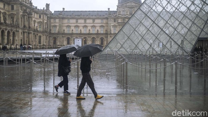 People walk by the Louvre museum, in Paris, France, Sunday, March 1, 2020. The spreading coronavirus epidemic shut down Frances Louvre Museum on Sunday, with workers who guard its trove of artworks fearful of being contaminated by the museums flow of visitors from around the world. (AP Photo/Rafael Yaghobzadeh)