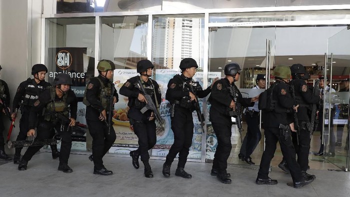Police enter a mall in Manila, Philippines Monday, March 2, 2020. Philippine police on Monday surrounded the shopping mall in an upscale section of Manila after a recently dismissed security guard opened fire and took dozens of people hostage, an official said. (AP Photo/Aaron Favila)