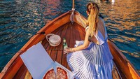 Kamu bisa menikmati sekotak pizza khas Italia dengan bir dingin sambil berlayar di atas perahu kayu yang menyusuri Cinque Terre. Foto: Instagram @cinqueterretrip