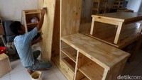 Seorang pekerja tengah menyelesaikan pembuatan furniture.