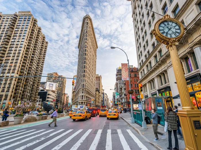 New York, New York, USA - April 15, 2013: Pedestrians stroll below the Flatiron Building. Finished in 1902, the landmark skyscraper was designated a City Landmark in 1966 and a National Historic Landmark in 1989.