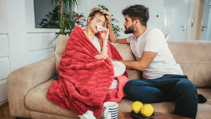 Shot of a young man comforting his sick girlfriend at home
