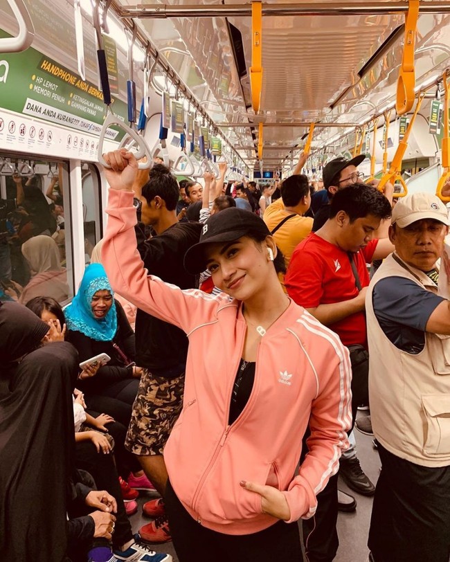 Vanessa Angel terlihat sporty dengan jaket berwarna pink muda dan topi hitam. Dalam foto tersebut Vanessa terlihat berpose di tengah keramaian dalam MRT. Foto: Instagram @vanessaangel