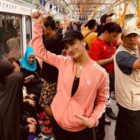 Vanessa Angel terlihat sporty dengan jaket berwarna pink muda dan topi hitam. Dalam foto tersebut Vanessa terlihat berpose di tengah keramaian dalam MRT. Foto: Instagram @vanessaangel