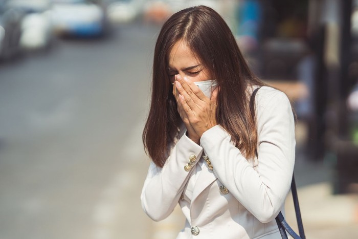 Asian woman are going to work.she wears N95 mask.prevent PM2.5 dust and smog.she is coughing