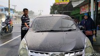 Dua orang warga hendak memasuki sebuah mobil yang tampak diselimuti abu akibat hujan abu yang mengguyur wilayah Klaten imbas erupsi Gunung Merapi, Selasa (3/3/2020).