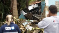 Sejumlah warga berdiri di depan sebuah mobil yang rusak usai hanyut terbawa air imbas banjir bandang yang menerjang kawasan Rio de Janeiro, Brasil, Senin (2/3/2020) waktu setempat.