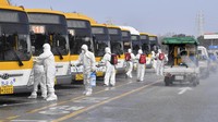 Para petugas dibantu tentara nasional Korsel menyemprotkan desinfektan untuk pencegahan corona di terminal bus Gwangju. Park Chul-hong / Yonhap via AP.