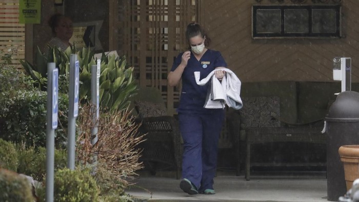 A worker at the Life Care Center in Kirkland, Wash., near Seattle, wears a mask as she leaves the building, Monday, March 2, 2020. Several of the people who have died in Washington state from the COVID-19 coronavirus were tied to the long-term care facility, where dozens of residents were sick. (AP Photo/Ted S. Warren)