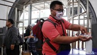 Seorang warga mengenakan masker pelindung pernapasan saat sedang menggunakan fasilitas antiseptik gratis yang disediakan di Stasiun Pasar Senen, Jakarta, Rabu (4/3/2020).