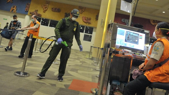 Awak kabin berjalan di dekat alat penyemprot cairan disinfektan otomatis yang dipasang petugas Kantor Kesehatan Pelabuhan (KKP) Kelas I Denpasar di kawasan Terminal Domestik Bandara Internasional I Gusti Ngurah Rai, Bali, Selasa (3/3/2020). Kegiatan desinfeksi yang dilakukan di area terminal domestik dan internasional bandara tersebut dilakukan sebagai salah satu langkah antisipasi potensi penyebaran COVID-19 atau virus Corona. ANTARA FOTO/Fikri Yusuf/aww.