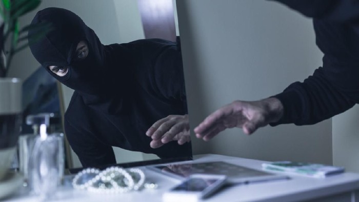 Thief in balaclava breaking into the house