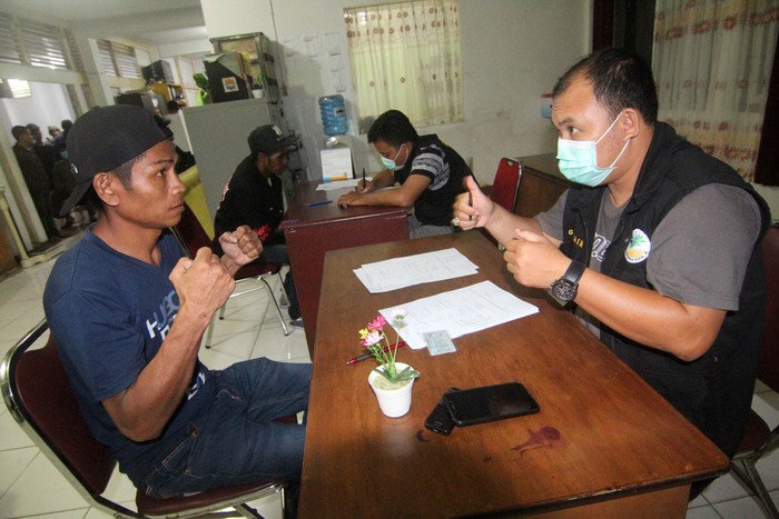 MALAYSIA DEPORTASI PMI BERMASALAH Seorang Pekerja Migran Indonesia (PMI) dan petugas Dinas Sosial Provinsi Kalbar menggunakan bahasa isyarat untuk berkomunikasi saat pendataan di Kantor Dinsos Kalbar di Pontianak, Selasa (3/3/2020) malam. BP3TKI Pontianak mencatat terdapat 100 PMI (91 pria, 9 wanita) bermasalah asal Kalbar, Nusa Tenggara Timur dan Nusa Tenggara Barat yang ditangkap Imigrasi Semuja Serian Malaysia lalu kemudian dipulangkan ke Indonesia karena tidak memiliki paspor dan dokumen ijin kerja. ANTARA FOTO/Jessica Helena Wuysang/hp.