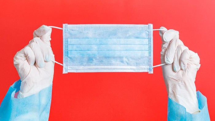 Masker Female hands in medical gloves holding protective mask at red background. Health care concept. Coronavirus concept