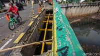 Warga yang ingin melintas pun harus rela berjalan di sisi jalan.