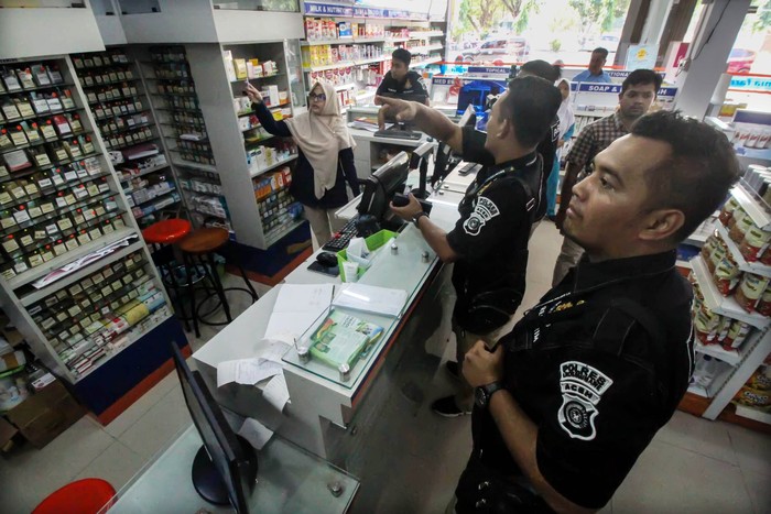 RAZIA PENIMBUNAN MASKER DI APOTEK Personel Polisi Satuan Reserse Kriminal menyerahkan surat perintah pemeriksaan kepada petugas apotek di Lhokseumawe, Aceh, Rabu (4/3/2020). Kepolisian Polda Aceh melakukan razia mendadak ke sejumlah apotek untuk mengecek stok masker dan hand sanitizer yang mulai sulit dicari, sekaligus upaya antisipasi penimbunan masker dan penggelembungan harga pasca pengumuman korban terjangkit virus corona di Indonesia,. ANTARA FOTO/Rahmad/ama.