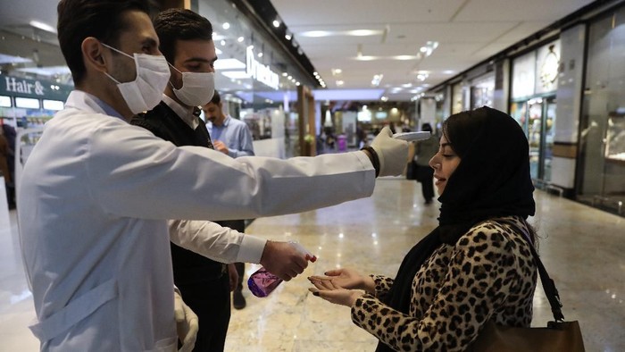 A woman has her temperature checked and her hands disinfected as she enters the Palladium Shopping Center, in northern Tehran, Iran, Tuesday, March 3, 2020. Irans supreme leader put the Islamic Republics armed forces on alert Tuesday to assist health officials in combating the outbreak of the new coronavirus, the deadliest outside of China. (AP Photo/Vahid Salemi)