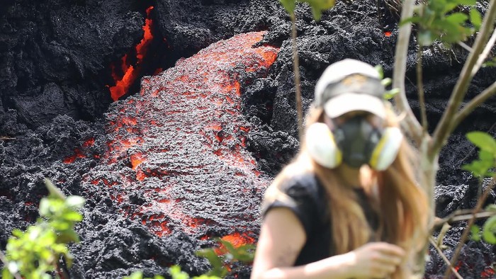 PAHOA, HI - MAY 12:  Lava flows at a new fissure in the aftermath of eruptions from the Kilauea volcano on Hawaiis Big Island as a local resident walks nearby after taking photos on May 12, 2018 in Pahoa, Hawaii. The U.S. Geological Survey said a recent lowering of the lava lake at the volcanos Halemaumau crater Òhas raised the potential for explosive eruptionsÓ at the volcano. Authorities have confirmed the fissure is the 16th to open.  (Photo by Mario Tama/Getty Images)
