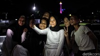 Tak sedikit warga yang berfoto bersama dengan latar warna-warni lampu yang menghiasi ibu kota di kawasan Lapangan Banteng.