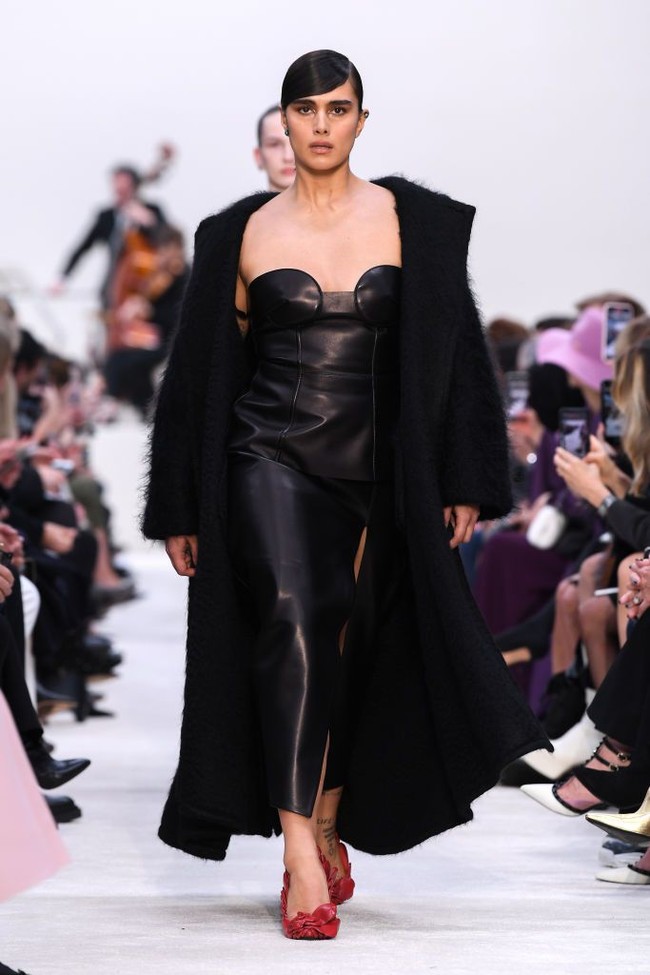 Model kelahiran Belanda ini menebar pesonanya dengan busana serba hitam. Jill memakai gaun kulit berbelahan tinggi pada bagian rok, berikut mantel hitam berpotongan minimalis sebagai luaran. Gayanya juga dilengkapi heels merah yang dihiasi motif kelopak bunga tiga dimensi. (Foto: Getty Images/Pascal Le Segretain)