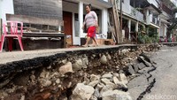 Seorang warga melintas diantara jalan yang amblas di kawasan Jalan Kesatriaan 10, Kebon Manggis, Matraman, Jakarta Timur, Kamis (5/3/2020).