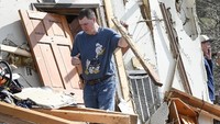 Terlihat seorang warga berupaya membersihkan puing-puing di depan halaman rumahnya. George Walker IV/The Tennessean via AP.