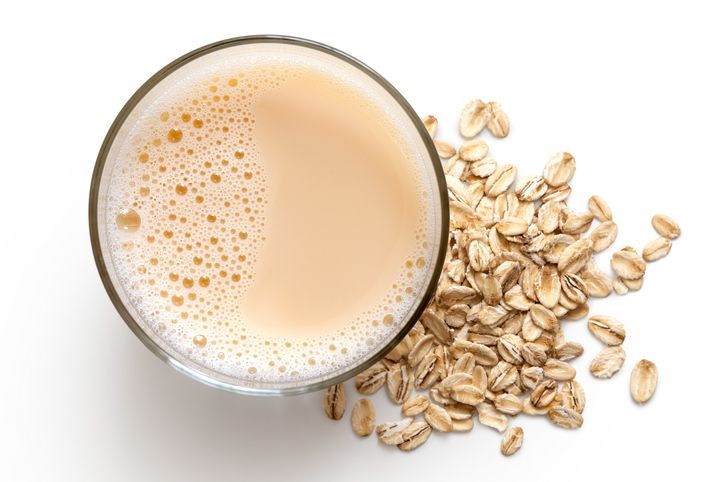 Oat milk in glass and jar on wood background, copy space