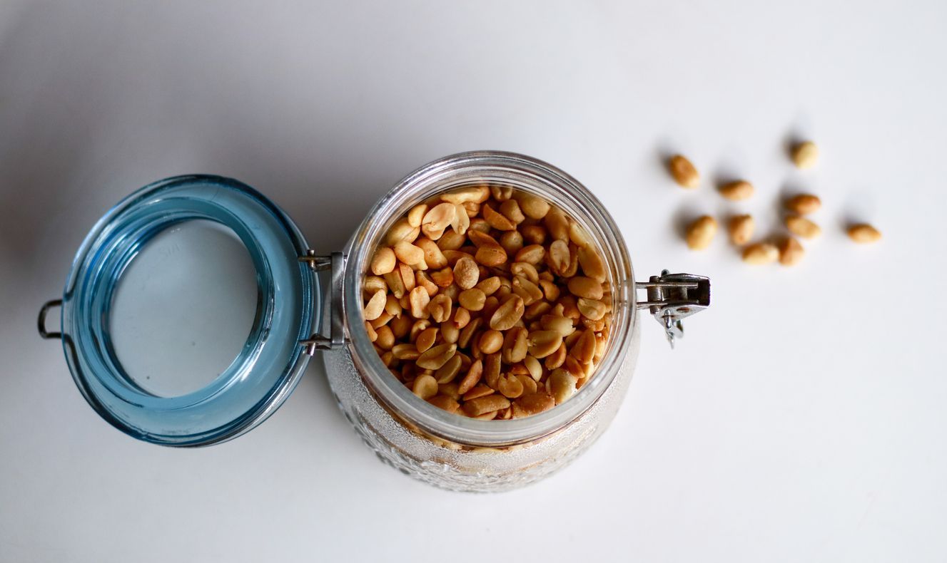 Fried peanuts in a jar on white background.
