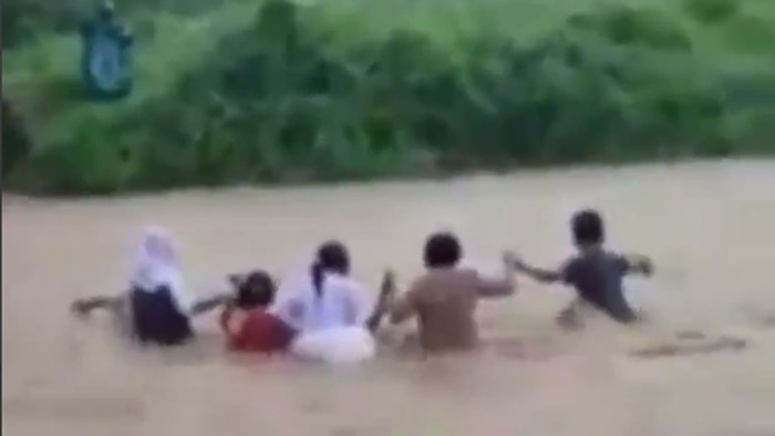 Tangkapan layar video viral guru dan siswa di Malut seberangi sungai deras.