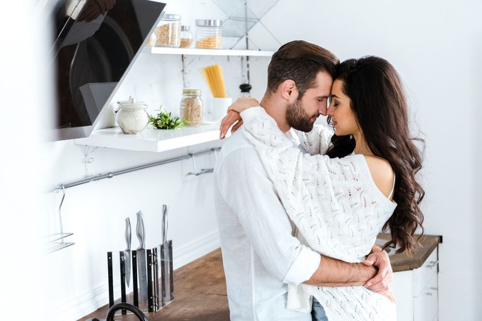 lovely gently couple embracing with closed eyes at kitchen